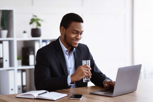 Smiling black manager reading sales report on laptop